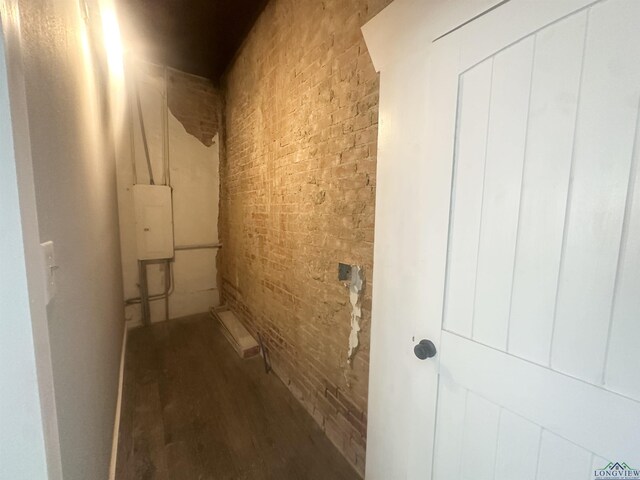 laundry room featuring brick wall and wood finished floors