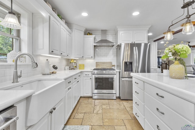 kitchen featuring a sink, appliances with stainless steel finishes, tasteful backsplash, and wall chimney exhaust hood