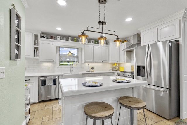 kitchen with wall chimney range hood, backsplash, a sink, stone tile flooring, and stainless steel appliances