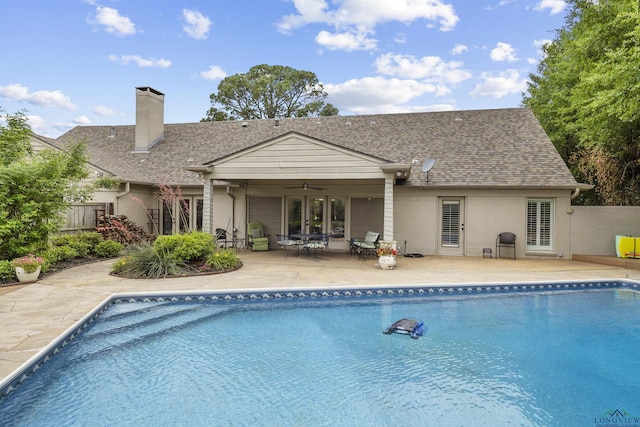 rear view of house with a shingled roof, fence, a fenced in pool, and ceiling fan