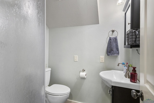 bathroom with baseboards, toilet, and vanity