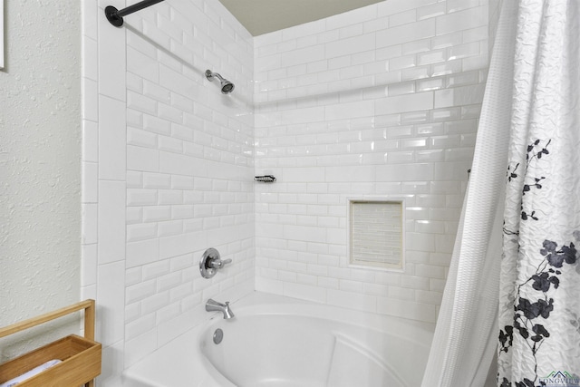 full bathroom with a textured wall and shower / bath combo