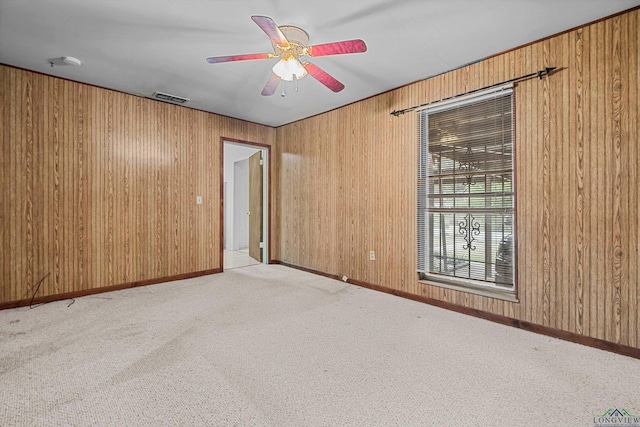 empty room with light carpet, ceiling fan, and wood walls