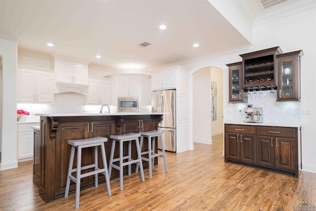 kitchen with a kitchen breakfast bar, arched walkways, light countertops, and appliances with stainless steel finishes