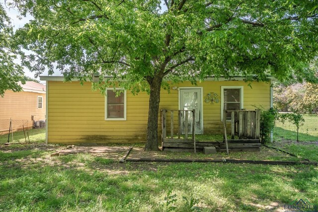 back of property with a lawn and fence
