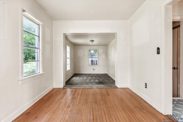 spare room with baseboards, plenty of natural light, and hardwood / wood-style flooring