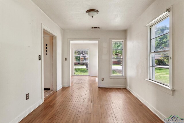 doorway to outside with baseboards, visible vents, and hardwood / wood-style flooring