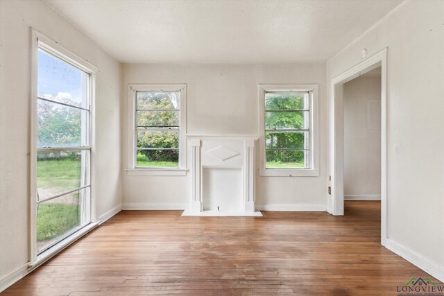 unfurnished living room featuring plenty of natural light, baseboards, and hardwood / wood-style floors
