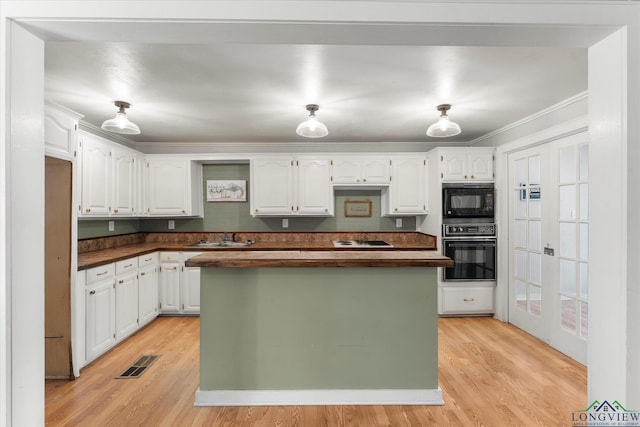 kitchen with white cabinets, a kitchen island, ornamental molding, and black appliances