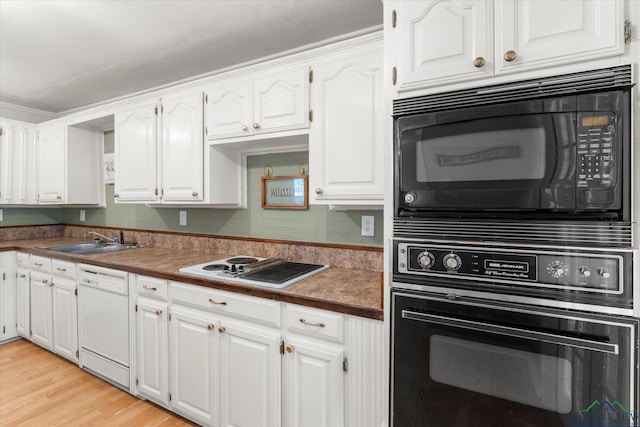 kitchen with black appliances, white cabinetry, sink, and light hardwood / wood-style flooring