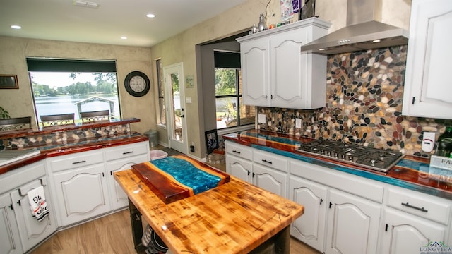 107 Kelly Ct, Marshall, TX 75672 - kitchen with stainless steel gas cooktop, wall chimney range hood, butcher block counters, decorative backsplash, and white cabinets