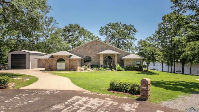 107 Kelly Ct, Marshall, TX 75672 - view of front of home featuring driveway, a front lawn, a chimney, an outdoor structure, and brick siding
