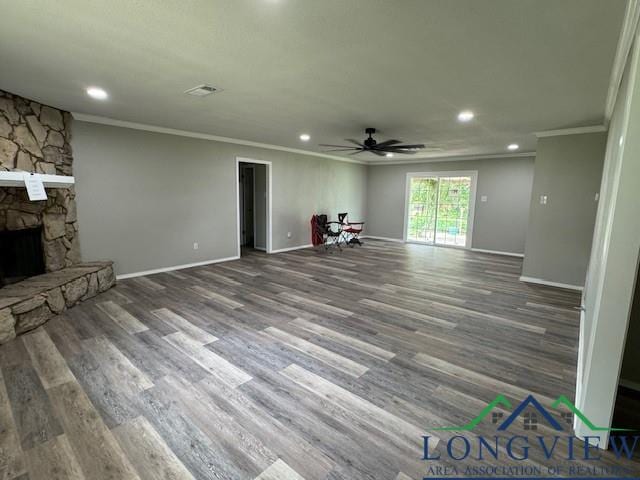 unfurnished living room with a stone fireplace, crown molding, hardwood / wood-style floors, and ceiling fan