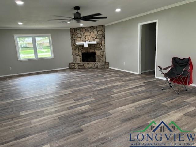 unfurnished living room featuring dark hardwood / wood-style floors, a stone fireplace, ceiling fan, and ornamental molding