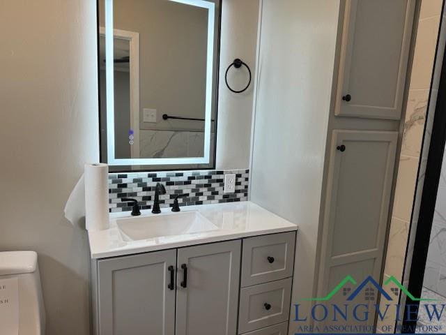 bathroom with decorative backsplash, toilet, and vanity