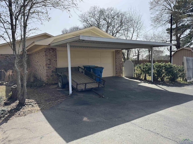 view of car parking featuring aphalt driveway, an attached garage, fence, and a storage unit