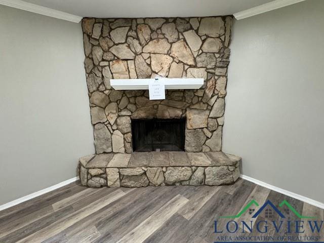 room details with baseboards, wood finished floors, a stone fireplace, and ornamental molding