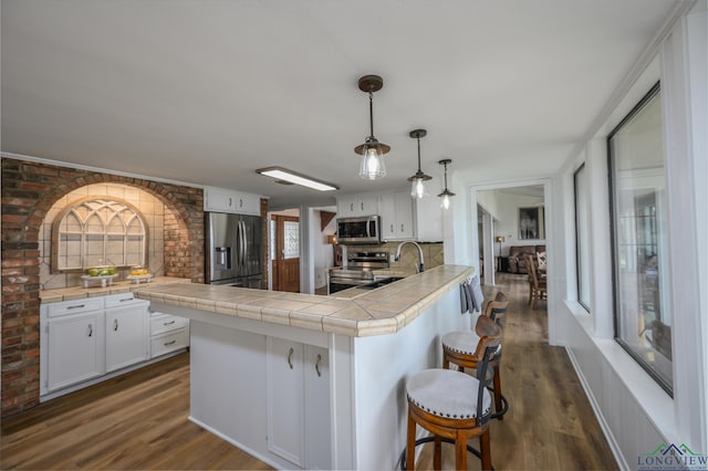 22551 Pine St, Frankston, TX 75763 - kitchen featuring stainless steel appliances, white cabinetry, a peninsula, a breakfast bar, and dark wood-style flooring