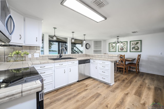 22551 Pine St, Frankston, TX 75763 - kitchen featuring stainless steel appliances, a peninsula, white cabinets, tile counters, and light wood finished floors