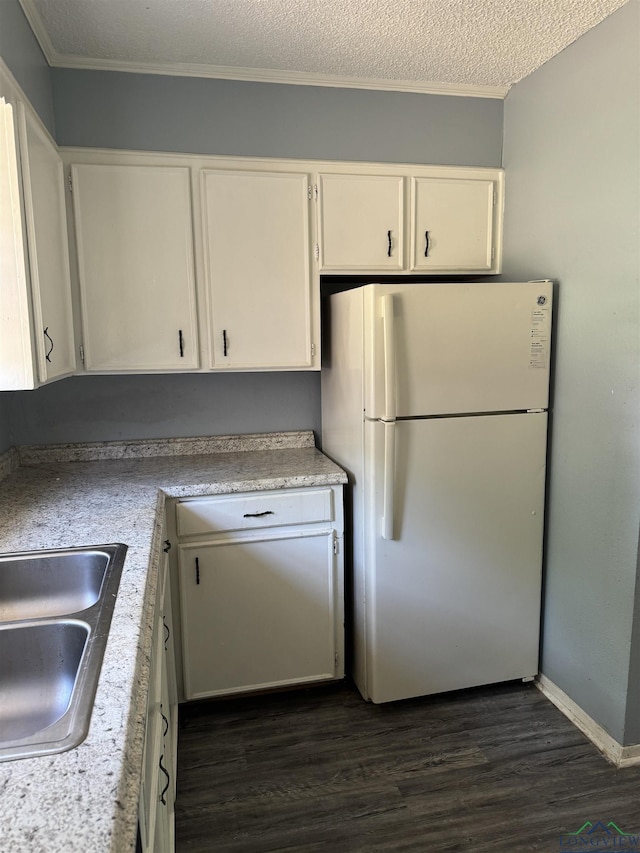 kitchen featuring sink, white cabinetry, dark hardwood / wood-style floors, white refrigerator, and a textured ceiling