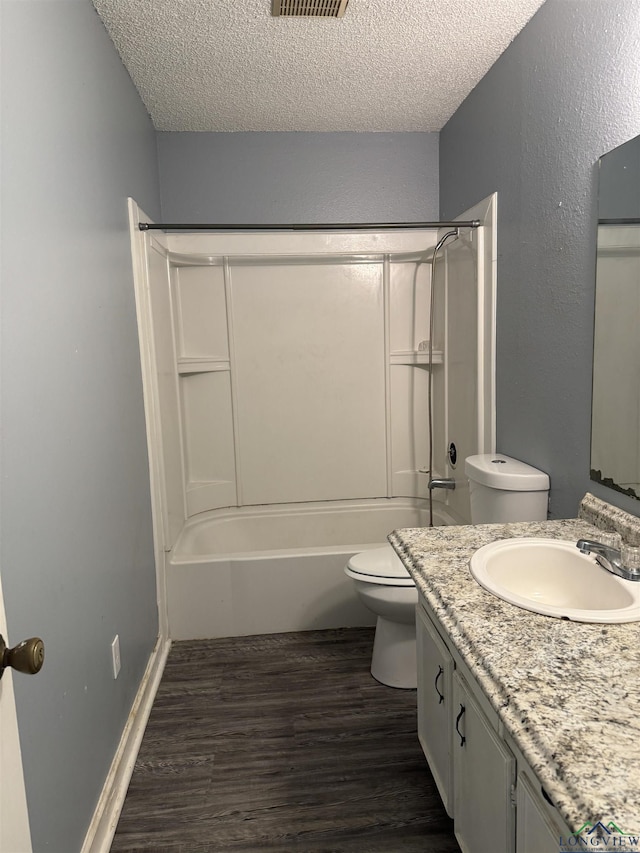 full bathroom featuring tub / shower combination, hardwood / wood-style floors, vanity, a textured ceiling, and toilet