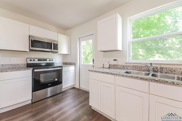 801 W Walnut St, Longview, TX 75601 - kitchen featuring appliances with stainless steel finishes, a sink, white cabinets, dark wood finished floors, and light stone counters