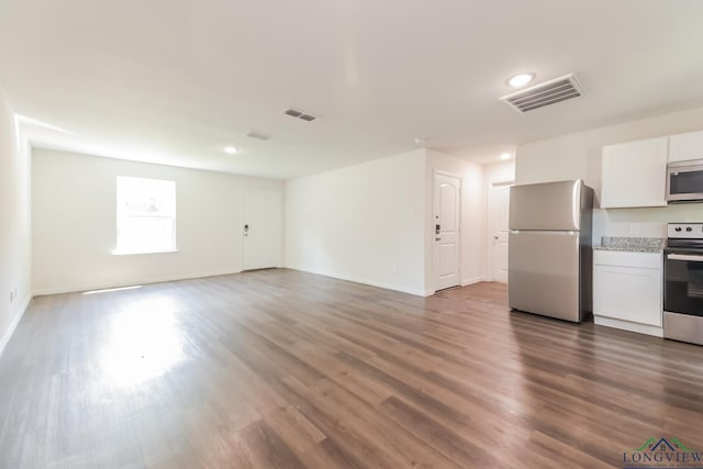 801 W Walnut St, Longview, TX 75601 - unfurnished living room featuring dark wood-type flooring, baseboards, and recessed lighting