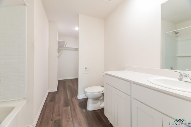 801 W Walnut St, Longview, TX 75601 - bathroom featuring wood finished floors, toilet, vanity, a spacious closet, and baseboards