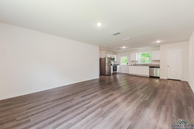 801 W Walnut St, Longview, TX 75601 - unfurnished living room with dark wood-style flooring, baseboards, and recessed lighting