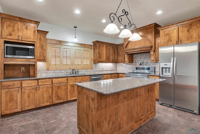 kitchen featuring sink, appliances with stainless steel finishes, hanging light fixtures, light stone counters, and a kitchen island