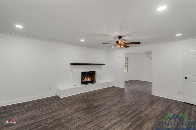 unfurnished living room with ceiling fan, dark hardwood / wood-style floors, ornamental molding, and a brick fireplace