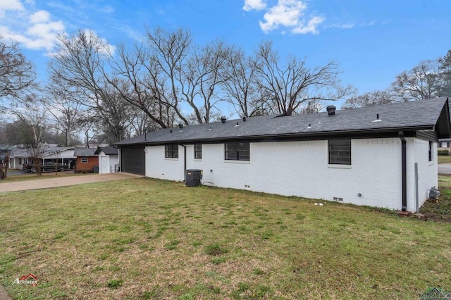 rear view of house with cooling unit, a yard, and a garage