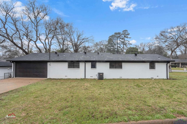 rear view of property featuring a garage, cooling unit, and a lawn