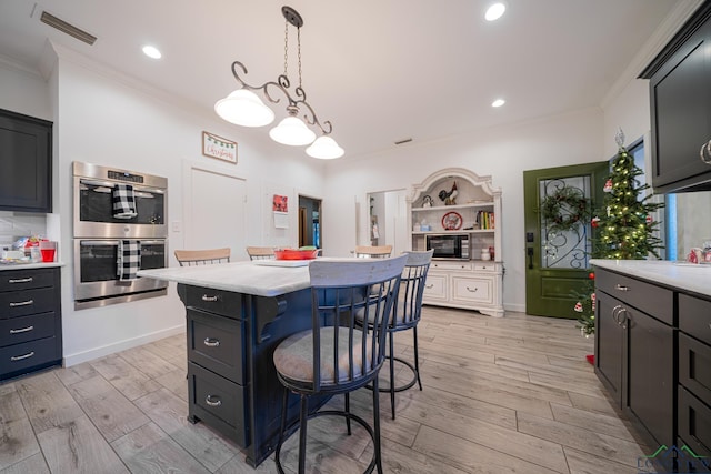 kitchen with a center island, double oven, pendant lighting, a kitchen bar, and ornamental molding