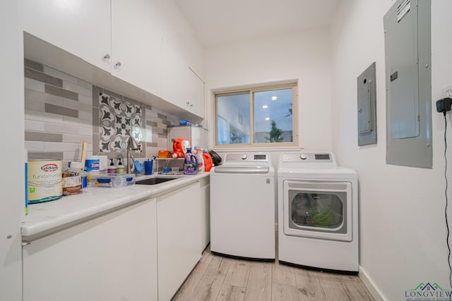 washroom with cabinets, independent washer and dryer, light wood-type flooring, and electric panel