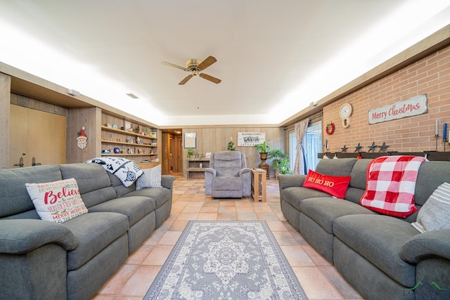 tiled living room with built in shelves, ceiling fan, and brick wall