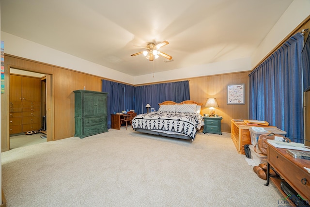 carpeted bedroom with ceiling fan and wood walls