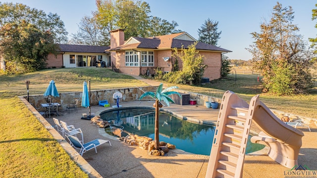 view of swimming pool featuring a yard, a patio, and a water slide