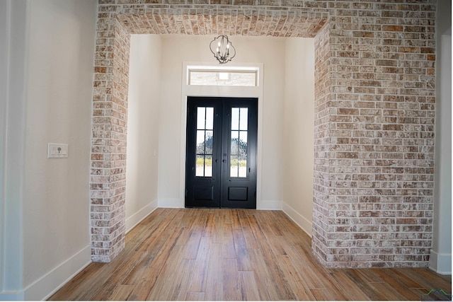 foyer entrance with french doors, a chandelier, and light hardwood / wood-style flooring