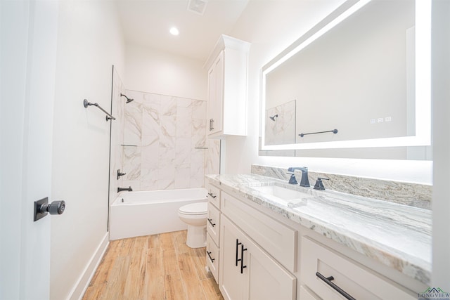 full bathroom with hardwood / wood-style floors, vanity, toilet, and tiled shower / bath