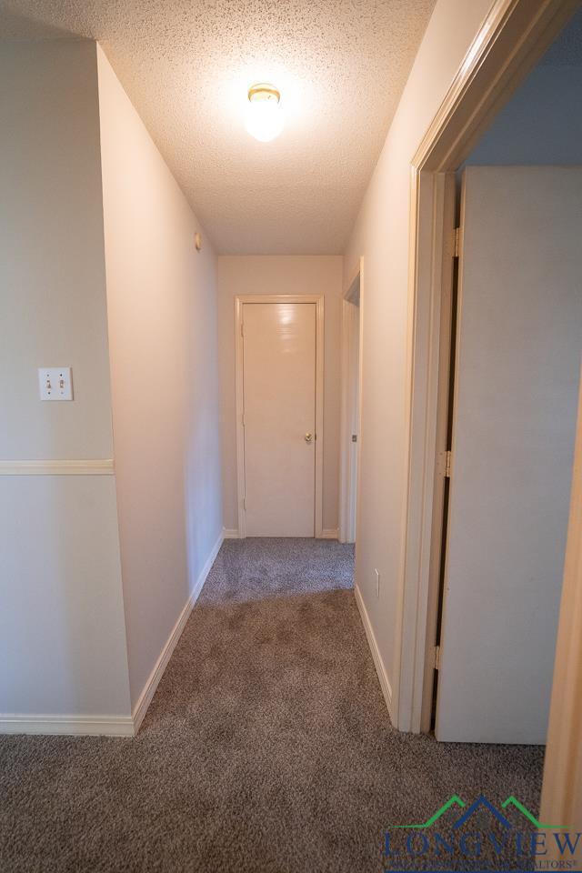 hallway featuring carpet and a textured ceiling