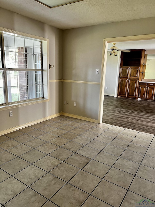 tiled spare room with ceiling fan and a textured ceiling