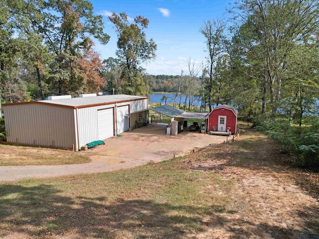 view of yard featuring a carport, a water view, a garage, and a storage unit