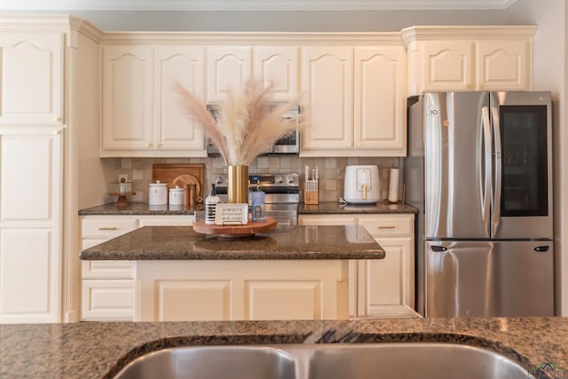 kitchen with tasteful backsplash, crown molding, appliances with stainless steel finishes, and dark stone counters