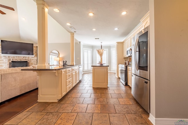 kitchen featuring kitchen peninsula, appliances with stainless steel finishes, pendant lighting, a fireplace, and a breakfast bar area