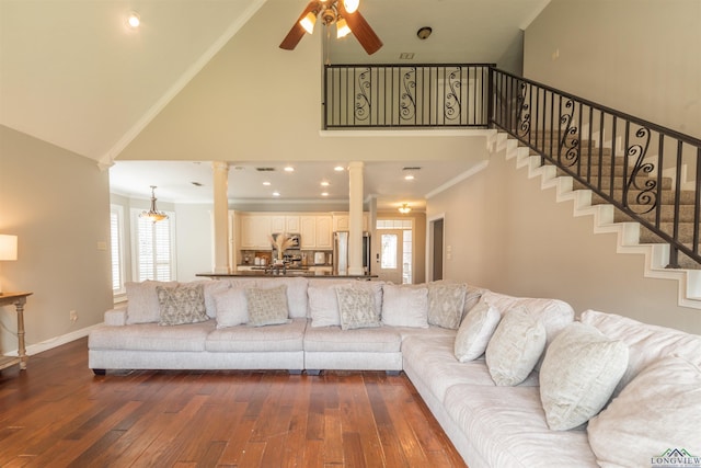 living room with a high ceiling, dark wood-type flooring, ceiling fan, and crown molding