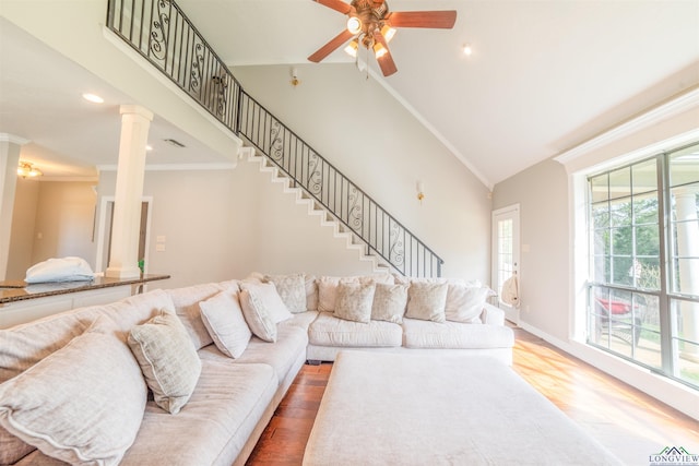 living room featuring ornate columns, ornamental molding, ceiling fan, wood-type flooring, and high vaulted ceiling