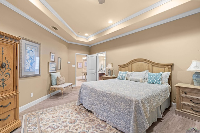 bedroom with a tray ceiling, ceiling fan, light hardwood / wood-style flooring, and ornamental molding