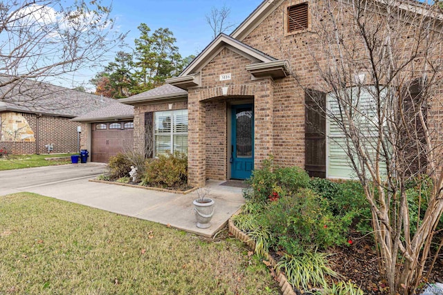 view of exterior entry with a yard and a garage