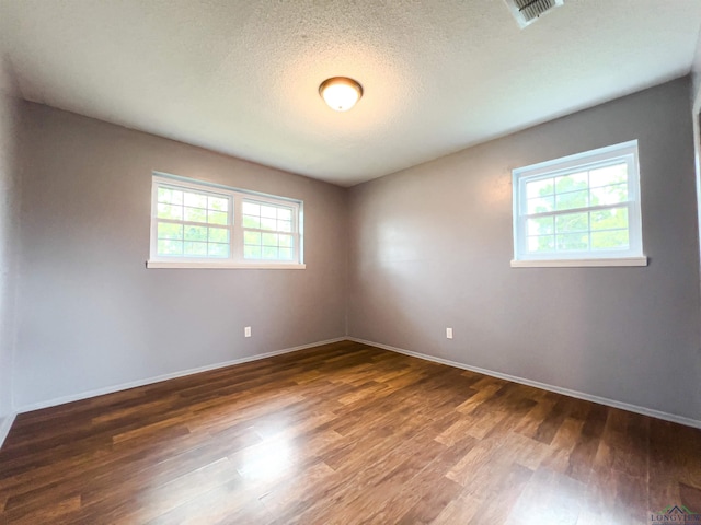 spare room with plenty of natural light, dark hardwood / wood-style floors, and a textured ceiling